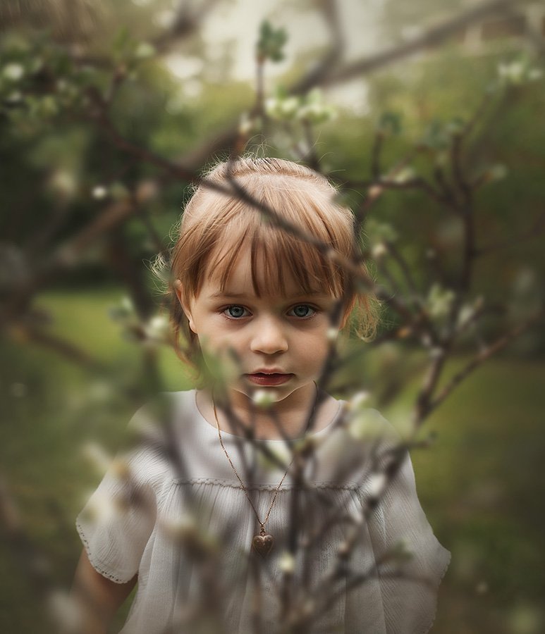 Porträtt av en flicka bakom grenar, sommar, grönt, Childphotography, Childportrait, Portrait of a girl behind branches, summer, green