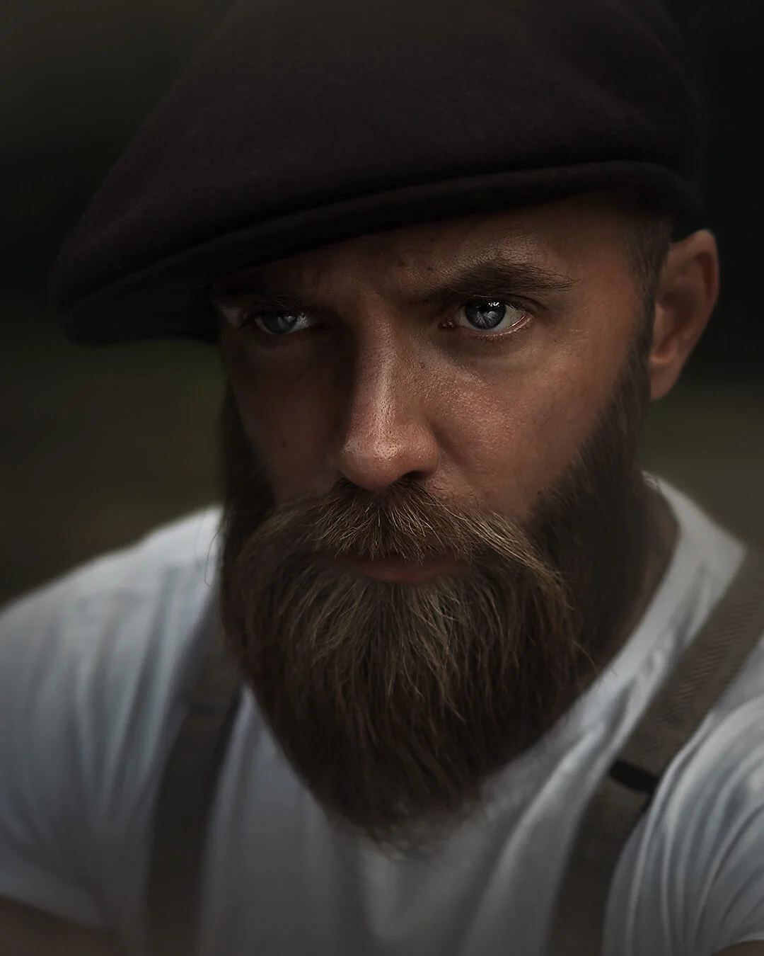Porträttfotografering - en man med skägg, intensiv blick, hängslen. Portrait photography - a man with a beard, intense gaze, braces.