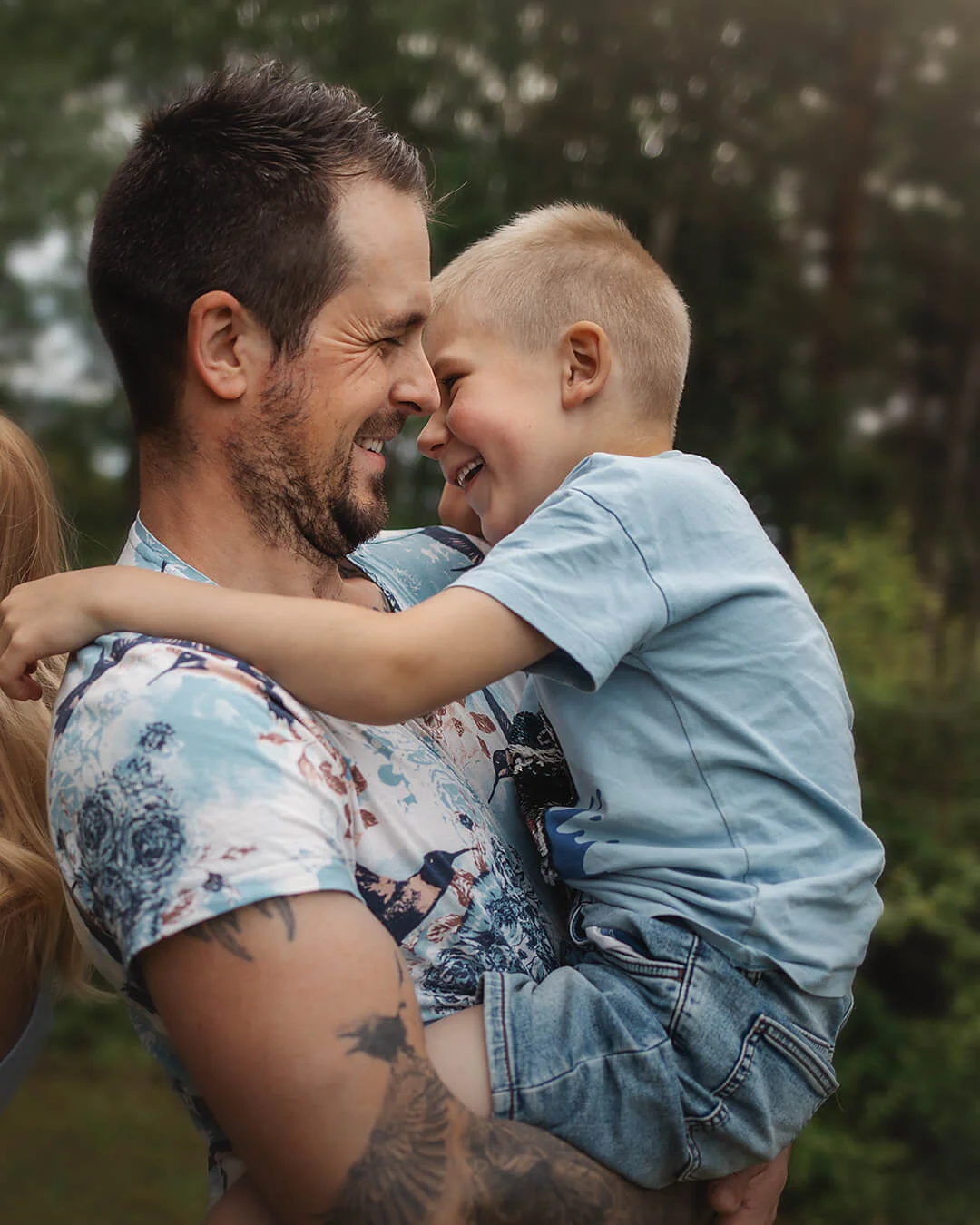Familjefotografering - far och son porträtt. Pappan har sonen i famnen och dom skrattar tillsammans. Family photography - father and son portrait. Familjeporträtt Sala. Familjekärlek. The father holds his son in his arms and they laugh together.
