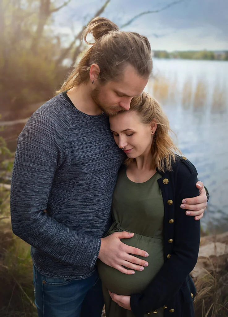 Gravidfotografering - parfotografering, porträtt på paret som väntar barn. Dom håller om varandra och tittar ner på gravidmagen. gravidfoto Strängnäs. Pregnancy photography - couple photography, portraits of the couple expecting a baby. They hold each other and look down at the pregnant belly.