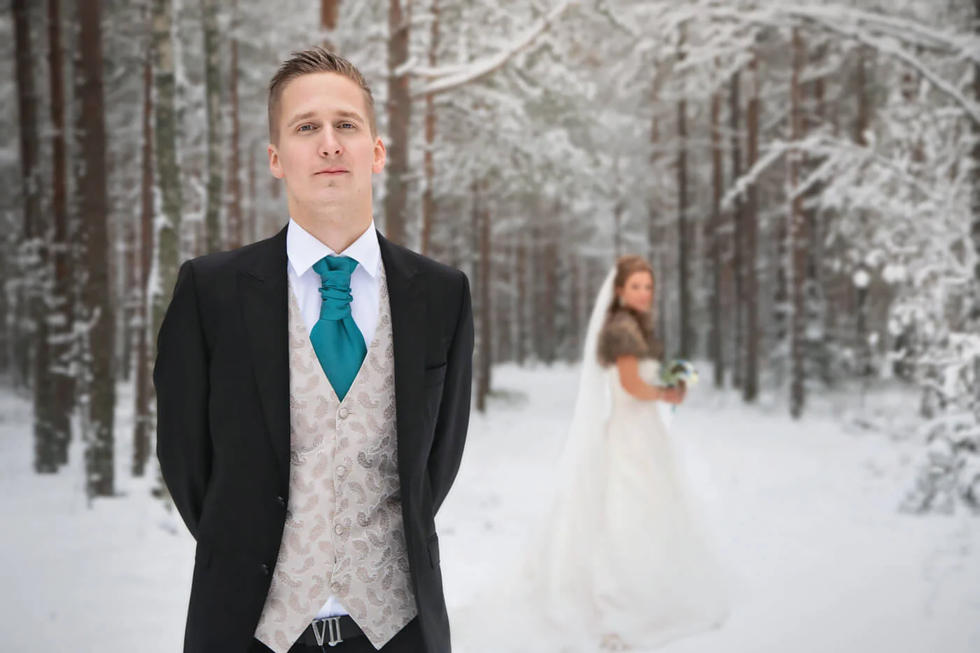 Bröllopsfotografering - vinterbröllop, brudgummen i fokus och bruden i bakgrunden. Fotografering, heby, uppsala län. Wedding photography - winter wedding, the groom in focus and the bride in the background.