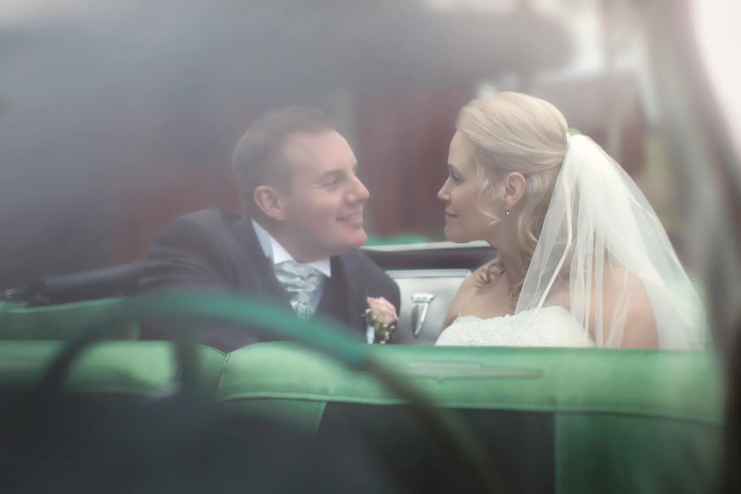 Bröllopsfotografering - porträtt på brudparet sittandes i en grön bil. Wedding photography - portrait of the bride and groom sitting in a green car.