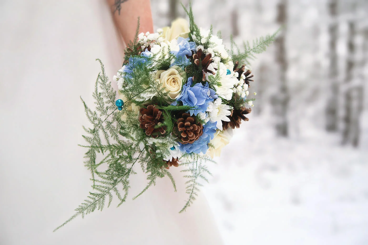 Bröllopsfotografering - vinterbröllop. brudbukett med blåa och beige/gula blommor och kottar. Wedding photography - winter wedding. bridal bouquet with blue and beige/yellow flowers and cones.