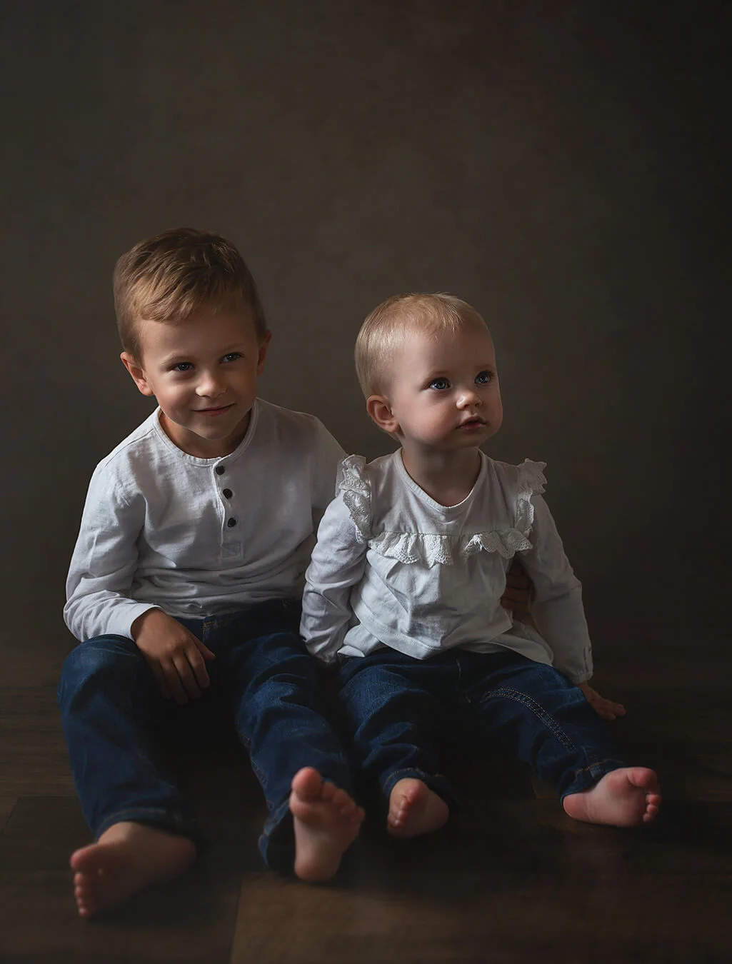 Barnfotografering - syskonfotografering - en pojke och en flicka sitter på golvet. studiofoto. Child photography - sibling photography - a boy and a girl sitting on the floor. studio photo.